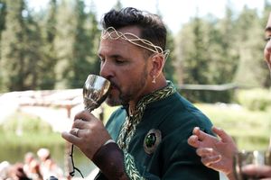 Wedding guests toasting with champagne glasses at an outdoor forest celebration.