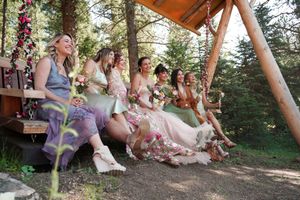 Wedding guests sitting on wooden benches in a rustic outdoor forest setting during a ceremony.
