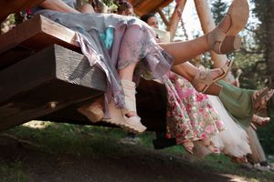 Wedding attendees show off their stylish footwear while sitting together outdoors.