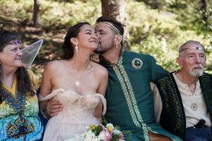 Wedding celebration outdoors with group sharing laughter in traditional medieval-inspired attire.