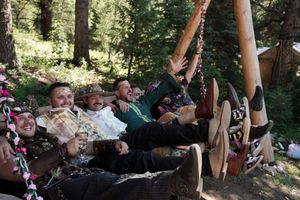 Wedding party enjoying candid moments together in a wooded outdoor setting.