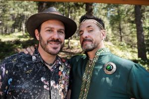Groomsmen in green and embroidered attire celebrate at outdoor forest wedding.