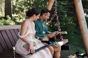 Romantic outdoor wedding moment captured in a forest setting with wooden benches.