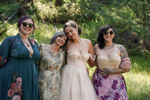 A group in colorful dresses posing together at an outdoor wedding celebration.