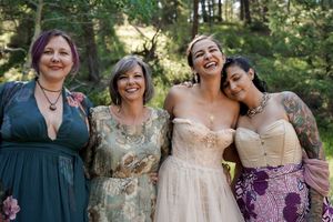 A group poses together in coordinated formal attire during an outdoor forest celebration.