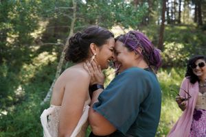A tender moment shared between newlyweds in a sunlit forest setting during their wedding celebration.