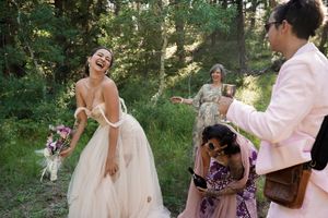 Joyful celebration moment during an outdoor forest wedding with attendees in formal attire.