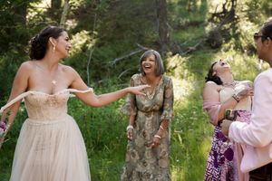 Wedding attendees share a playful moment during an outdoor forest celebration.