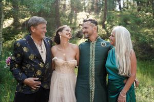 Wedding party members laugh together in a casual outdoor forest setting.