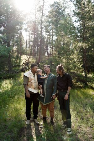Friends enjoying a relaxed moment together in a sunlit forest clearing with lush greenery and pine trees.