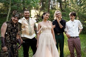 Wedding celebration group photo in a forest with people dressed in formal and fantasy-themed attire.