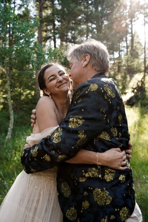 A joyful moment captured between a couple during their wedding celebration in a sunlit forest.