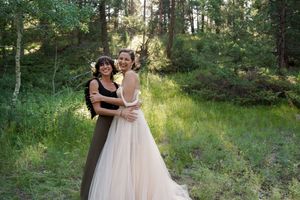 Wedding party enjoying a joyful outdoor celebration in a sun-dappled forest setting.