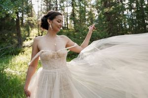 Flowing white wedding dress billowing gracefully in the sunlit forest.