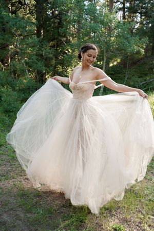 An ethereal white tulle wedding dress spins in a dreamy forest backdrop.