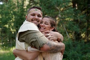 A romantic outdoor wedding moment in a sunlit forest clearing.