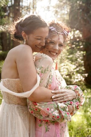 Two people in formal attire share joyful embrace during outdoor celebration.