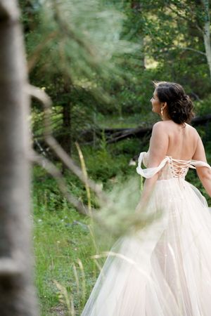 A flowing white wedding dress twirls gracefully in a forest setting.