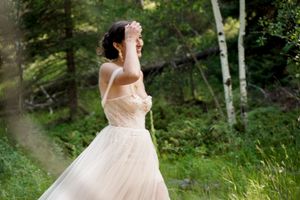 An elegant off-shoulder wedding dress captured in natural forest lighting.
