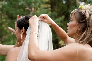 Close-up details of wedding dress adjustments and final touches in natural outdoor lighting.