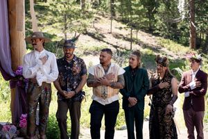 Wedding guests lined up for festivities in a rustic outdoor forest setting.