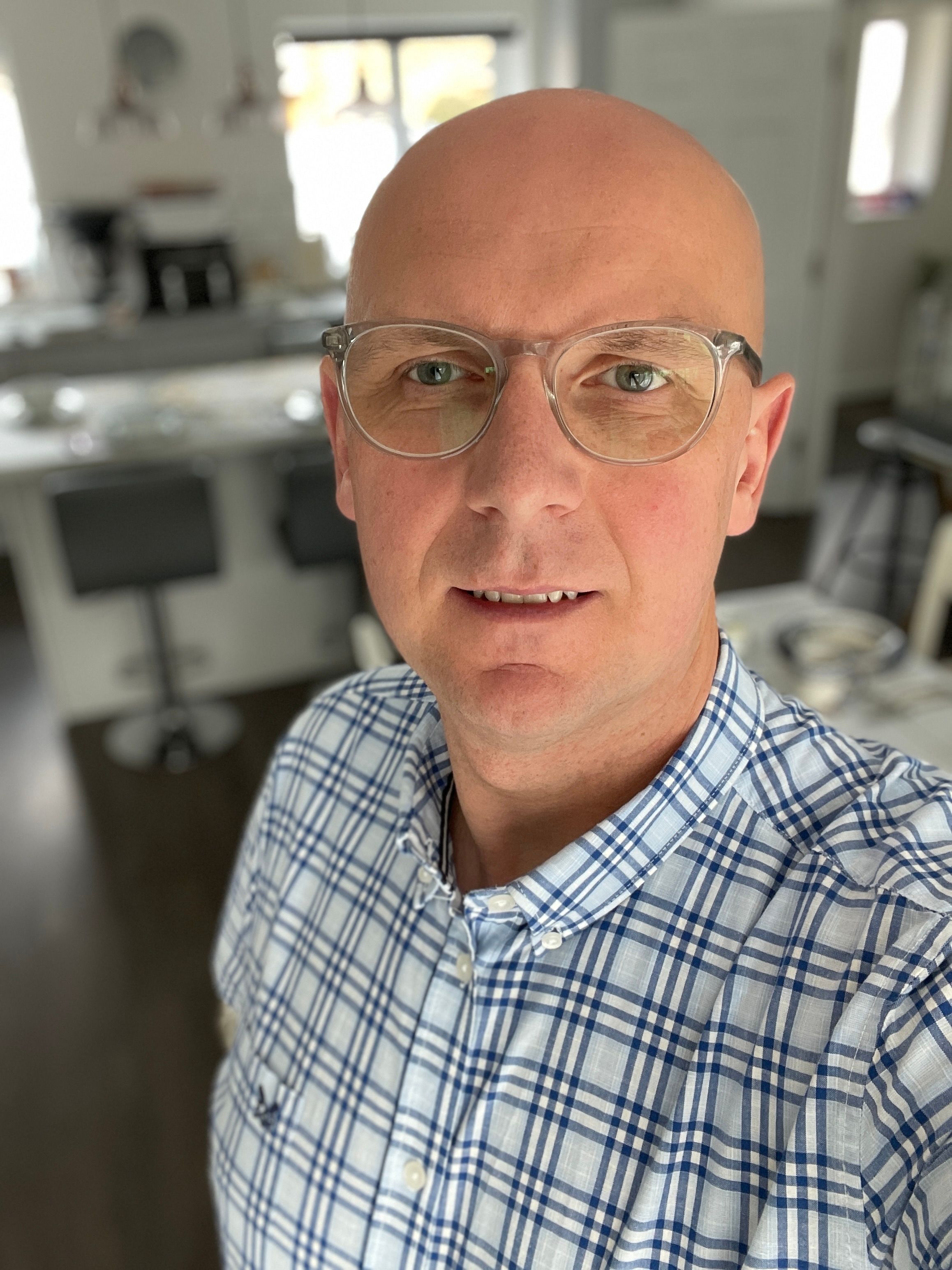 Person wearing glasses and checkered shirt in home office setting.