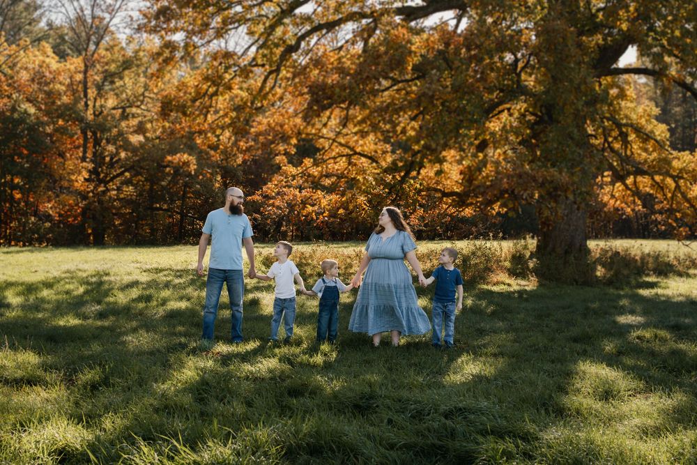 A group enjoying a sunny autumn day in a park with golden trees and fallen leaves in the background.