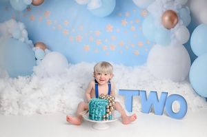 Birthday setup with blue balloons, clouds and turquoise cake for second birthday party.