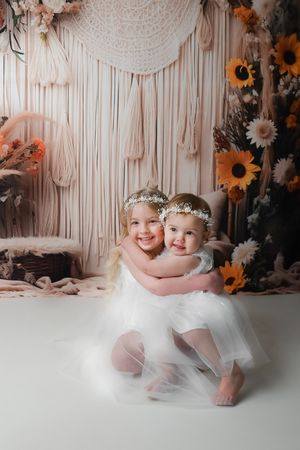 Elegant photo sequence with floral backdrop and macrame showing little ones in white tulle dresses.
