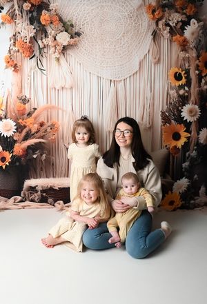 Family photo session with autumn-themed backdrop featuring sunflowers and macrame wall hanging.