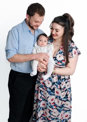 Family wearing coordinated blue and floral outfits smiling together during a professional photo shoot.