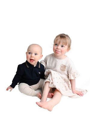Six milestone images showing a baby's growth milestones while wearing white outfits against a light background.