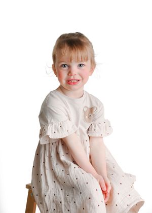 Sweet portrait series showing a child in a delicate white dress against a clean background.