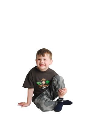 Child in gray shirt and jeans posing playfully on white background.