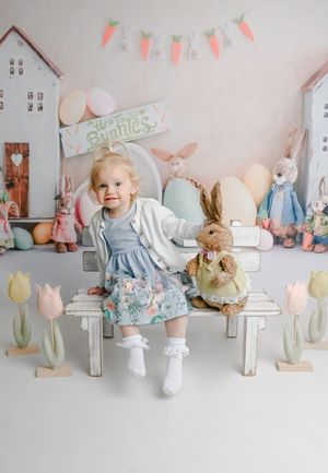 Easter-themed photo setup with pastel decorations and bunny toys on white shelves.