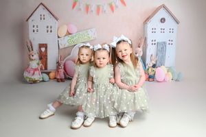 Sweet pastel nursery scene with white house decorations and soft toys arranged against pink backdrop.
