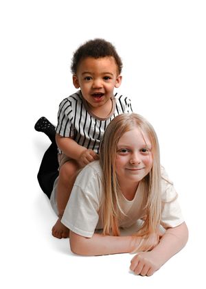 Two children lying on white background in playful poses.
