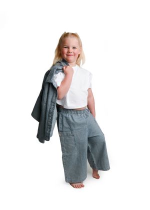 Child wearing gray linen pants and white shirt holding denim jacket in various poses.
