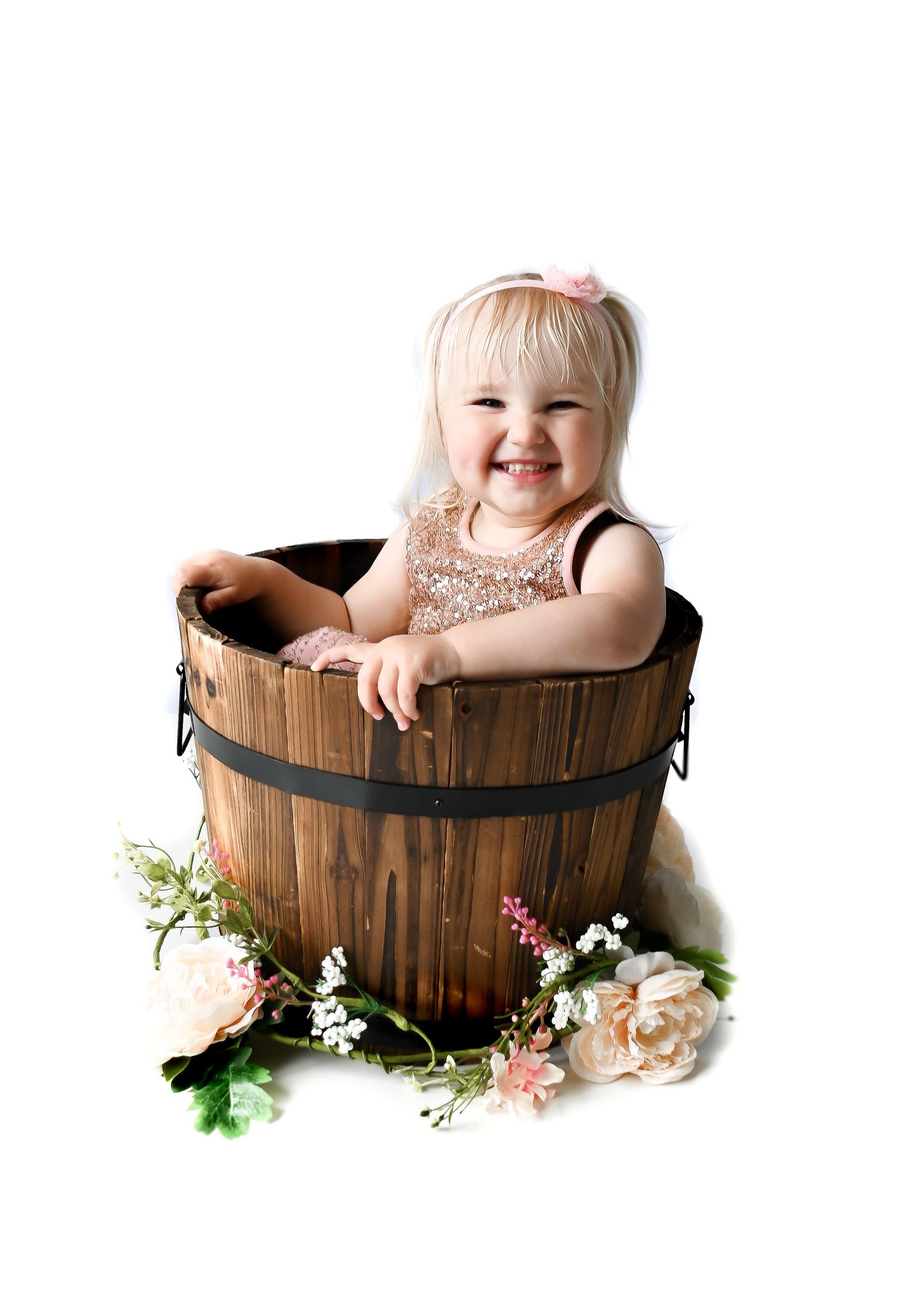 Baby photography series featuring rustic wooden barrel prop with floral accents.