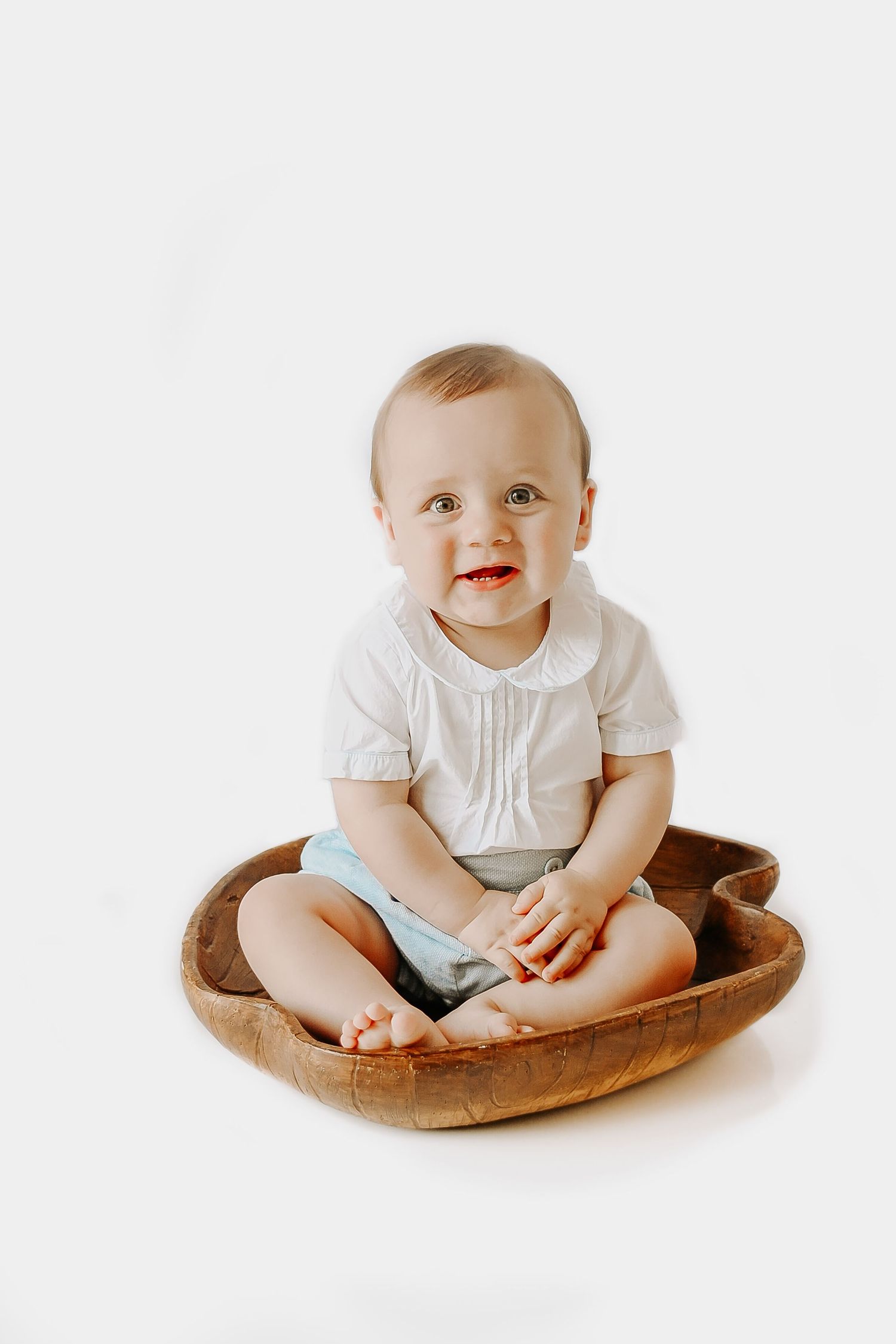 Studio portrait of baby sitting in brown cushion against white background.