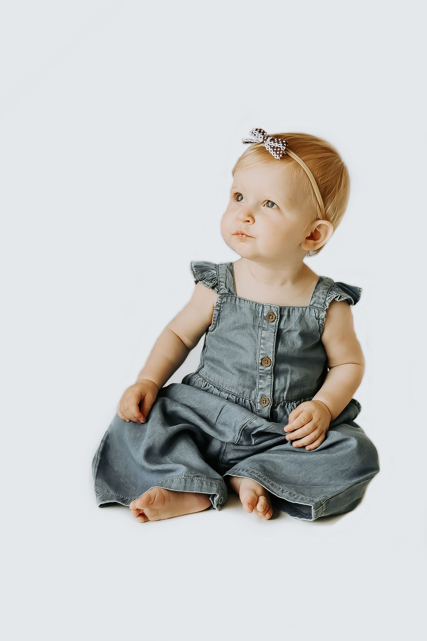 Baby portrait session featuring denim outfit and minimal white background.