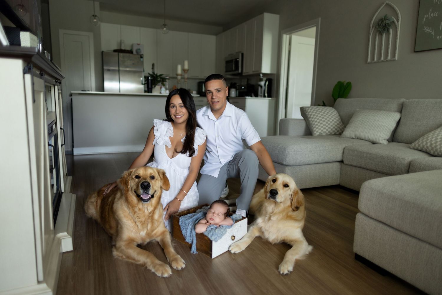 A family with a baby and two dogs pose together in a modern living room with white decor. Photos by Tampa Photographer DigitalMyst Photograp