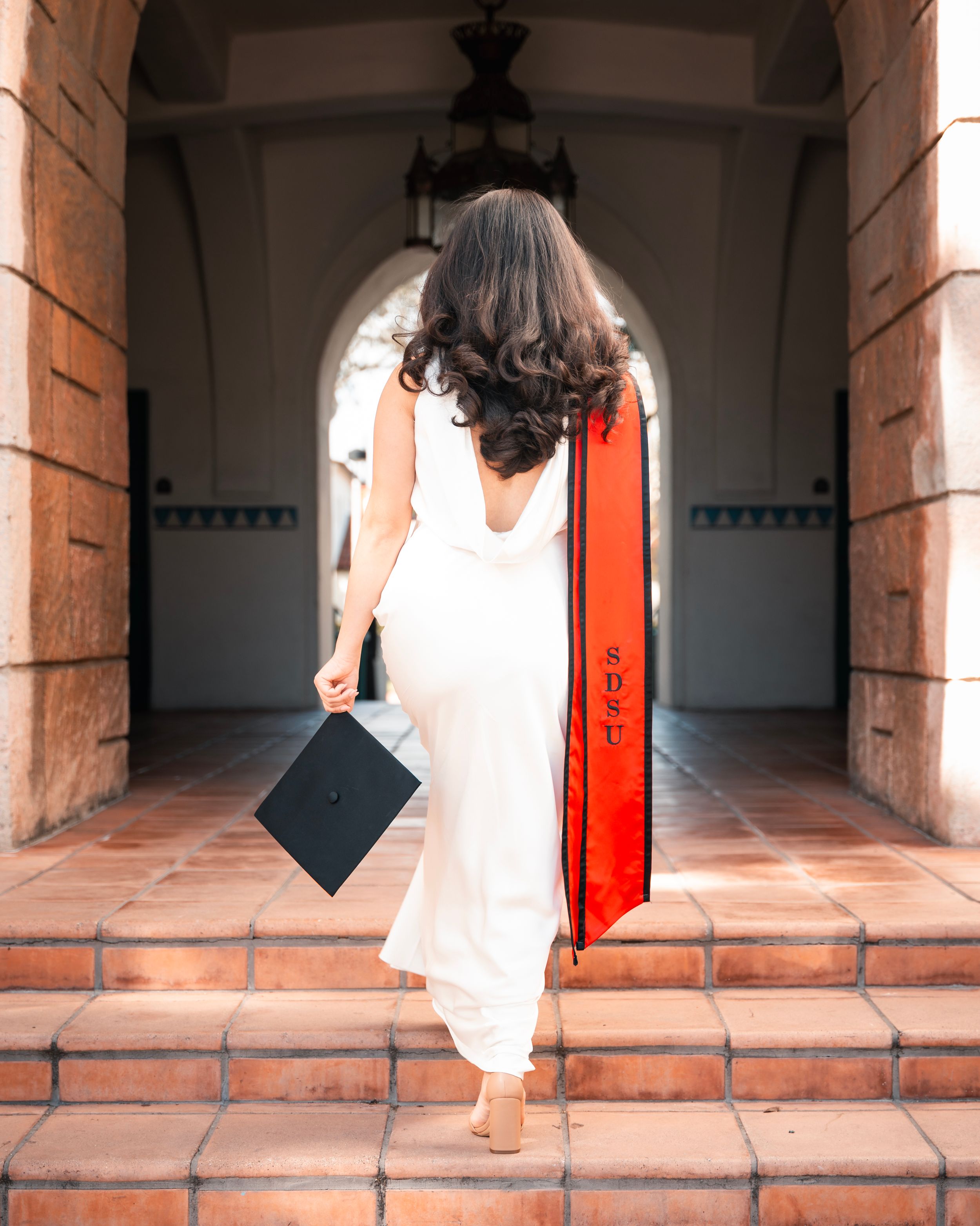 Artistic graduation photo series in stone archway with dramatic lighting and shadows.