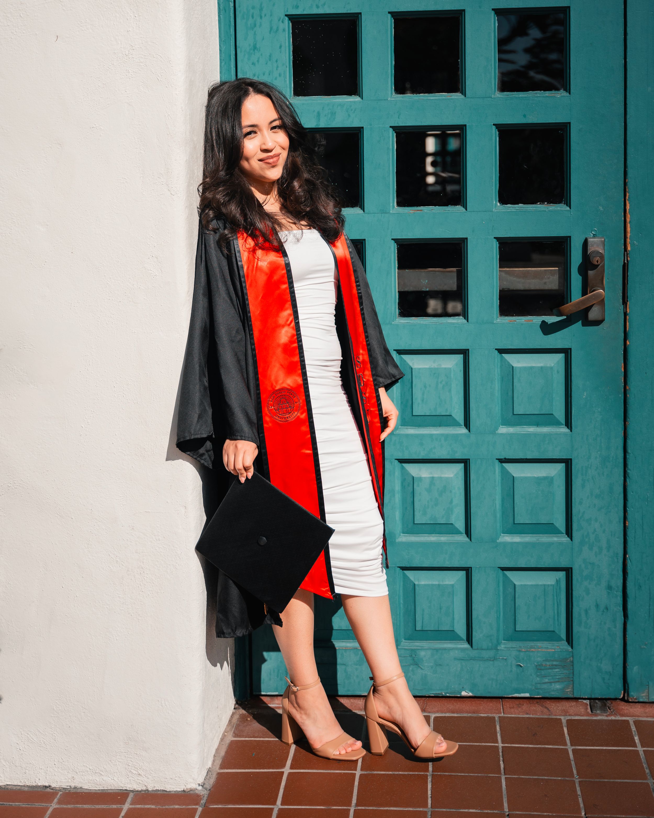Graduation photos featuring black cap and gown with red stole against turquoise doors.