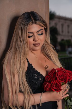 Portrait with red roses against architectural background in evening lighting.