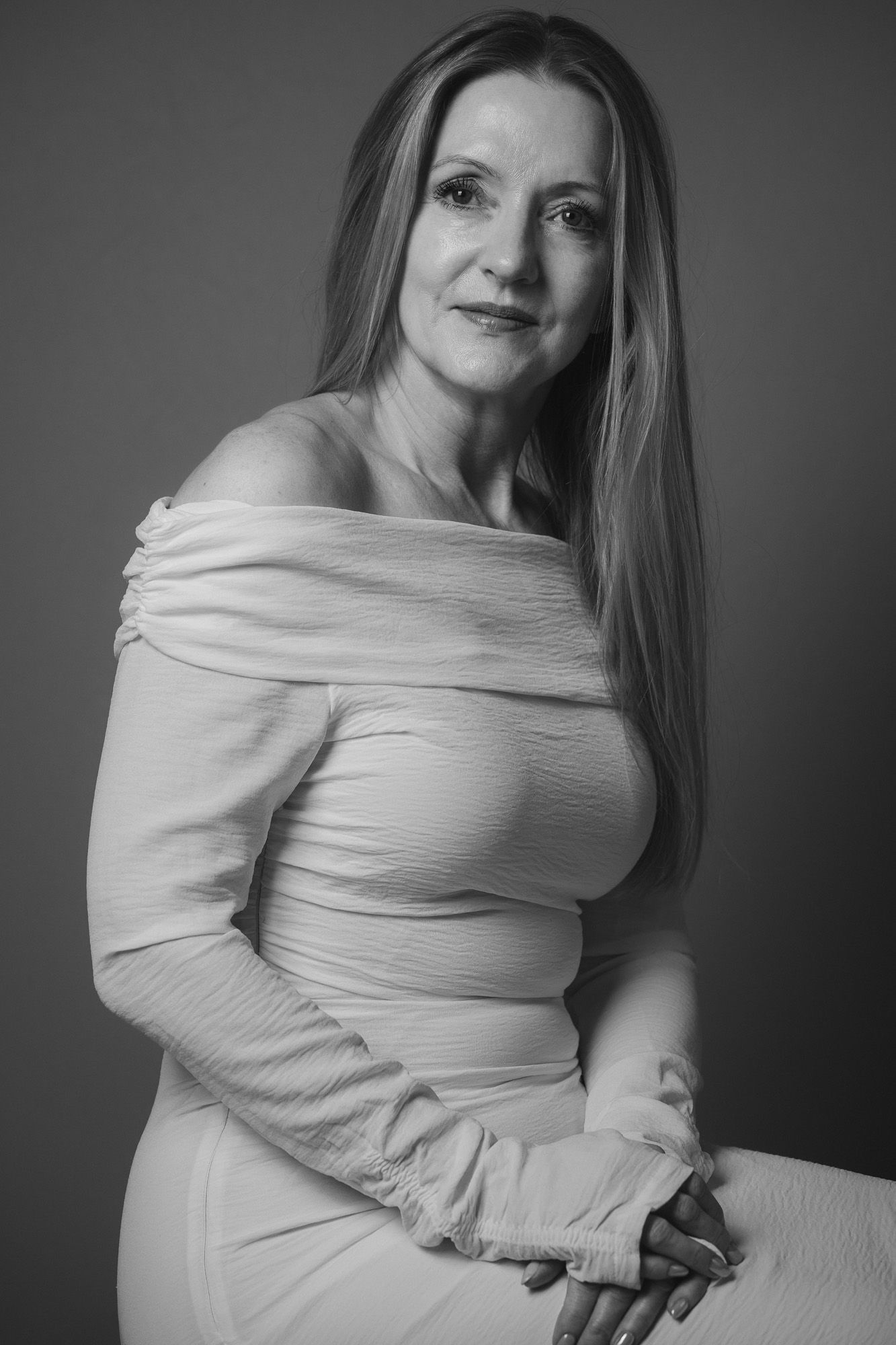 black and white female portrait of a woman in a white off-shoulder dress taken by N-lite photography in a studio in Norfolk