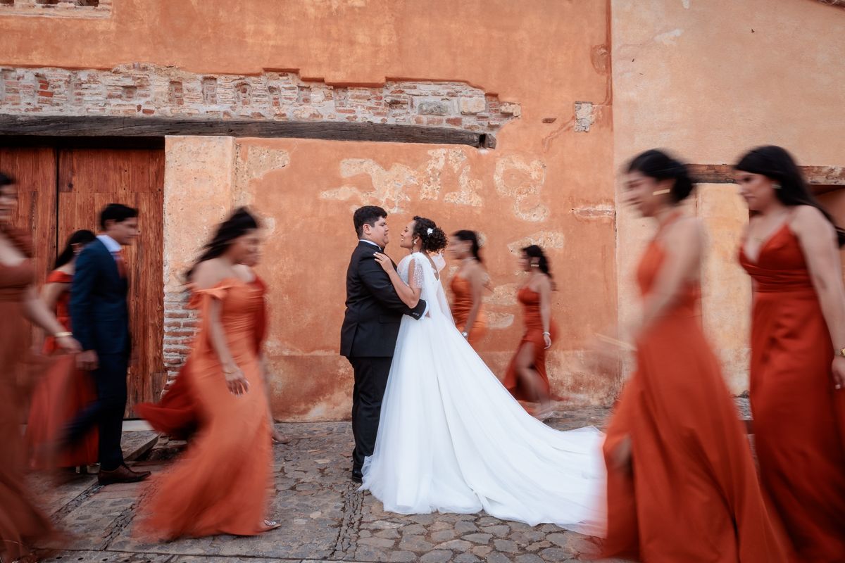 A series of artistic motion blur photos showing a wedding couple dancing against a rustic orange wall.