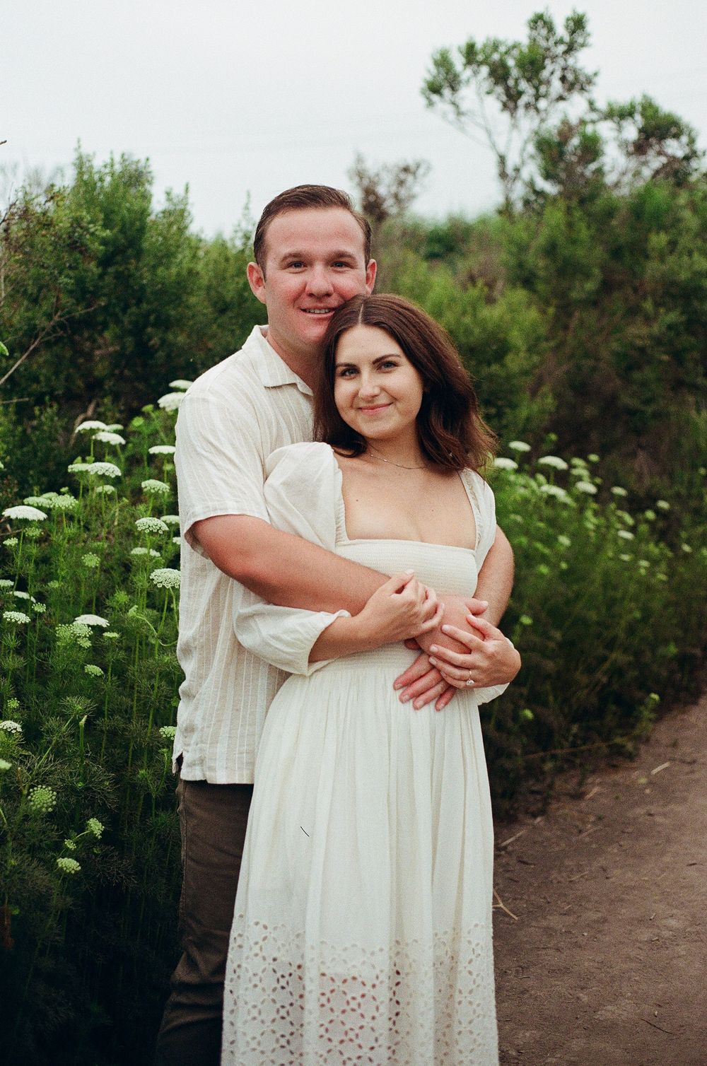 Carpinteria film photographer capturing an intimate couple's portrait with white flowers on the Carpinteria Bluffs.