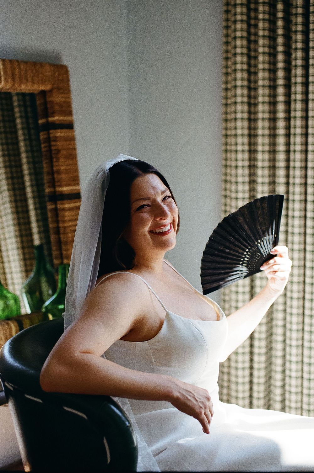 Bride on 35mm film fans herself while getting ready for her wedding day