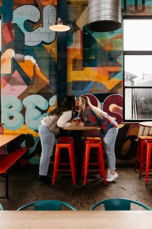 Interior of cafe with colorful graffiti wall art, red bar stools, and industrial lighting fixtures.